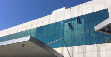 tecnicos em acesso por cordas limpando fachada de prédio